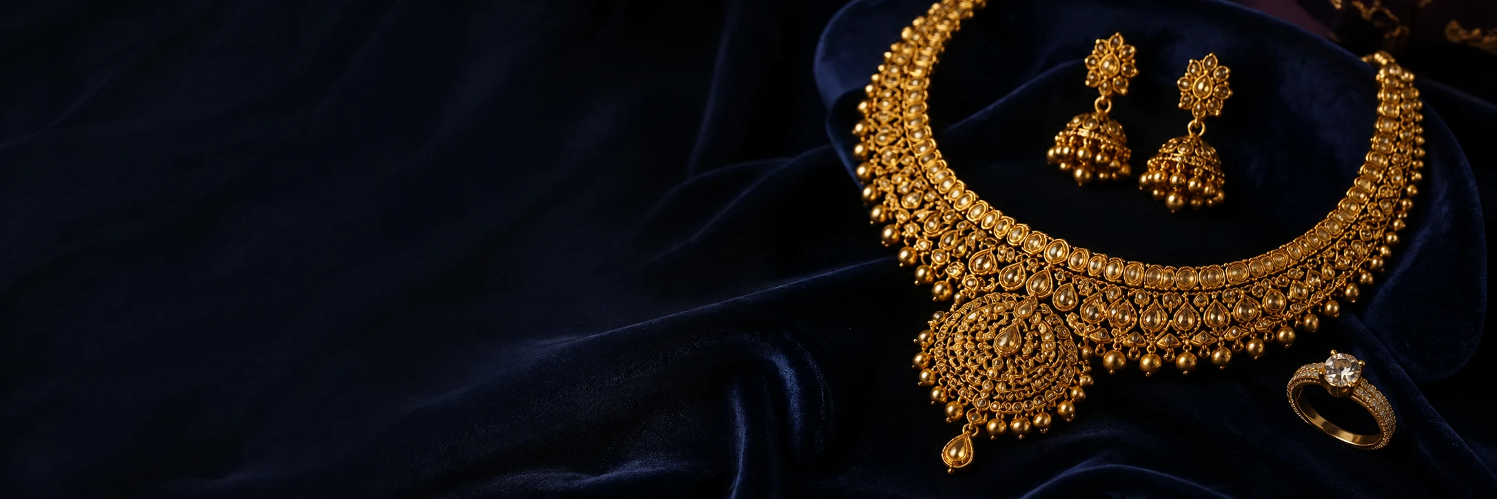 Illustrative image of a gold necklace, earrings and a ring on navy velvet